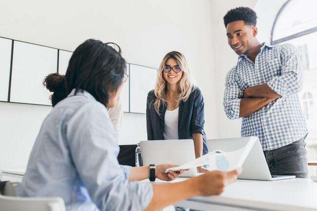 A team of business professionals in a conference room, with one person presenting data on a screen.