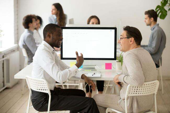 Two professionals discussing immigration case management at a computer