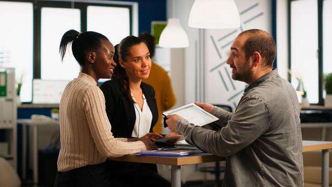 Three professionals having a discussion over a document in an office