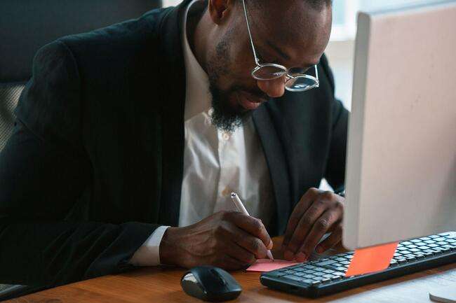 A focused lawyer writing notes at his desk, emphasizing meticulous immigration case management.