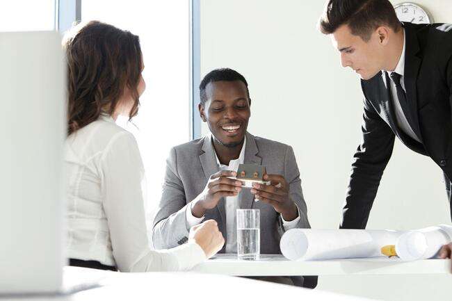 A group of business professionals having a discussion around a table, focusing on a document.