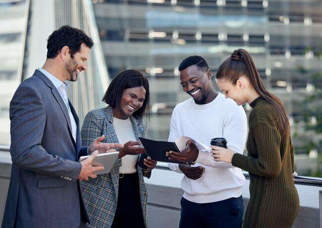 Group of diverse professionals reviewing a document on a tablet outdoors.