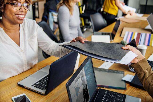 A team of legal professionals in an office, sharing documents and working on laptops, emphasizing collaboration and teamwork.