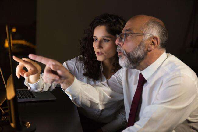 Two legal professionals working together on a computer screen, pointing and discussing details.