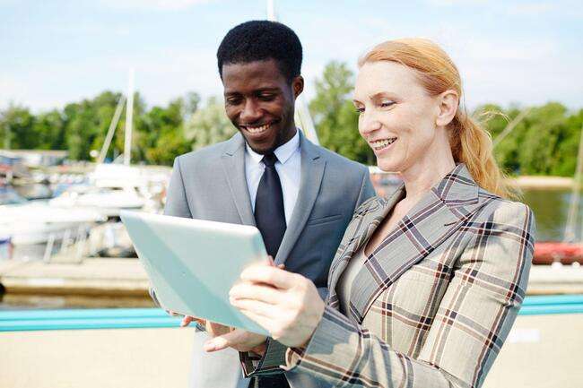 Two legal professionals using a tablet outdoors, discussing and collaborating on a case.