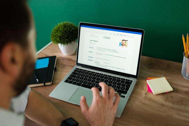 Professional reviewing a resume on a laptop