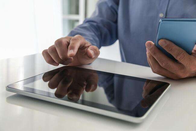 Person using a tablet and smartphone, interacting with a touch screen.