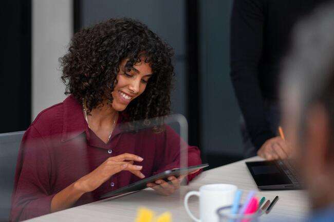 Smiling woman using a tablet in an office setting.